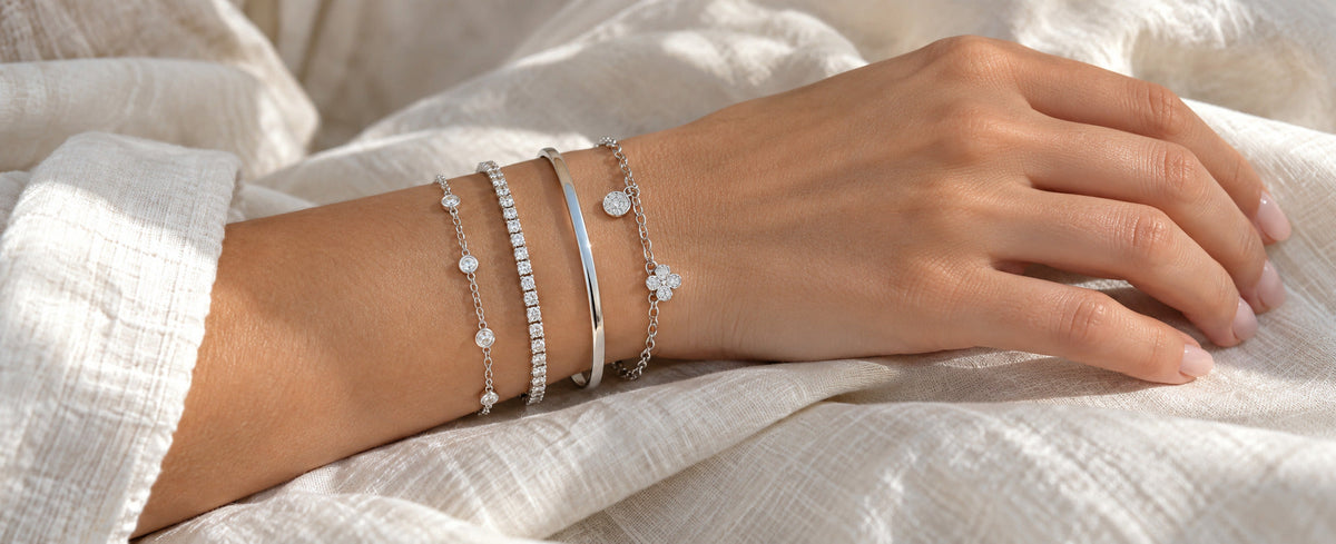 Balanced stack of silver chain tennis bangle and charm bracelets for Jewelry Towns guide