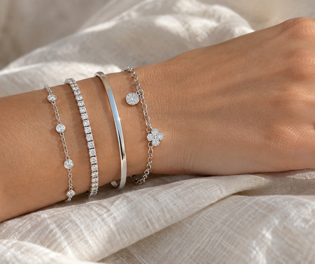 Balanced stack of silver chain tennis bangle and charm bracelets for Jewelry Towns guide