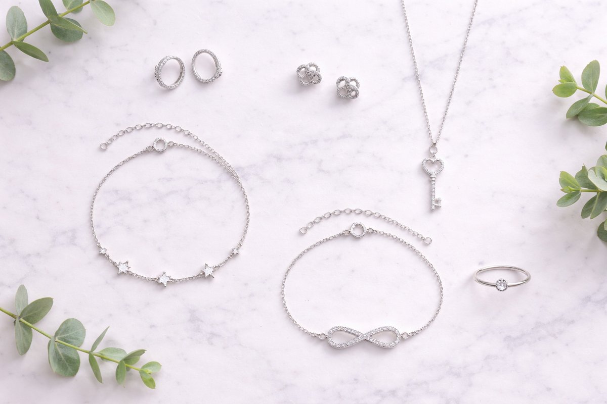 925 sterling silver jewelry flat lay on white marble with eucalyptus.