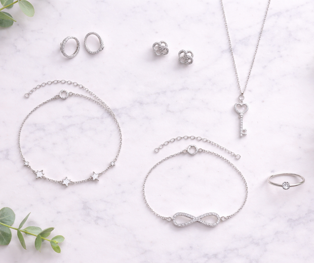925 sterling silver jewelry flat lay on white marble with eucalyptus.