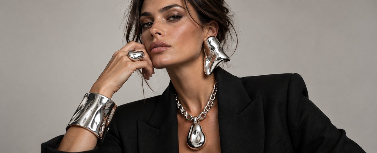 Woman wearing oversized sculptural silver jewelry for the 2026 curated maximalism trend