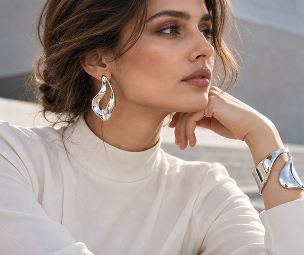 Woman wearing sculptural silver earrings and a polished silver cuff for the 2026 wearable art jewelry trend